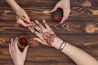 Artist making mehndi womans hand drinking tea