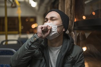 Front view sick man coughing bus while wearing medical mask