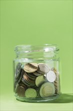 Close up coins inside glass container green background