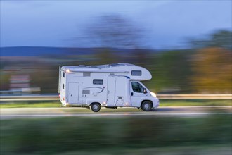 Motorhome driving on a country road at dusk