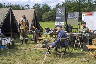 Re-enactors in World War Two battle dresses posing in military re-enactment field camp at WW2 militaria fair