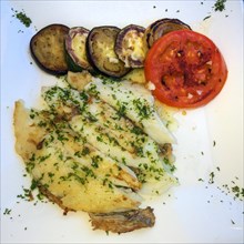 Mediterranean dish for healthy eating according to Italian recipe with sole Grilled sole fillet sprinkled with chopped parsley with lightly fried slices of aubergine Melanzane and tomato drizzled with...