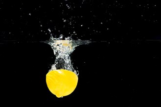 Halved lemon falling clean water against black background