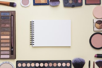 Overhead view spiral blank notepad surrounded with cosmetics product