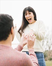 Young man proposing excited girlfriend