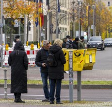 Tourists marvelling at and examining a yellow letterbox by the roadside