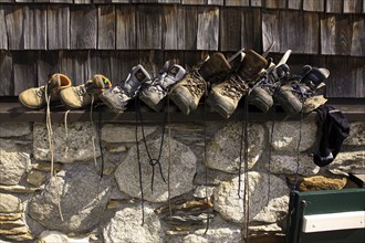 Mountaineering boots of hikers and climbers drying in the sun against wall of alpine mountain hut in the Alps