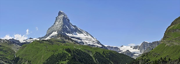 Panoramic view over the Matterhorn mountain with alpine meadows and pine forests in the Swiss Alps