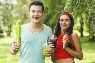 Smiling couple holding avocado apple smoothies hand