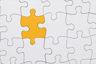 White jigsaw puzzle sheet with yellow puzzle piece center