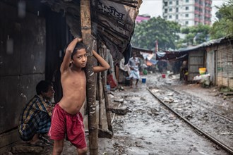 Boy under a canopy of an informal dwelling during a monsoon shower
