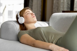 Medium shot woman couch with headphones