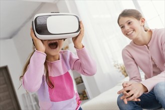 Two sisters home playing with virtual reality headset