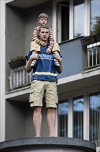 Realistic sculpture of a pillar saint father and son on a lift barrel pillar