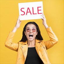 Woman yellow jacket holding sale banner medium shot