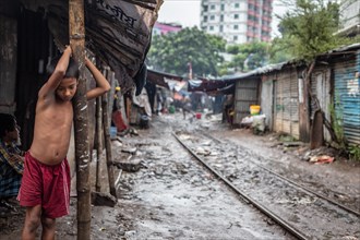 Boy under a canopy of an informal dwelling during a monsoon shower