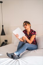 Attractive young woman reading a book in the hotel room