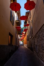 City Street in Porto Ceresio with Hanging Umbrellas in a Sunny Summer Day in Porto Ceresio
