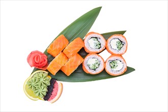 Overhead view of sushi roll with raw salmon fillet on top served on bamboo leaves
