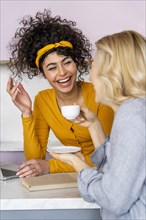 Two women laughing while having coffee