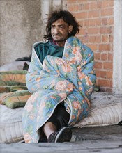 Homeless man mattress outdoors blanket