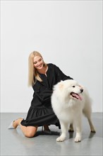 Happy blonde woman playing with her samoyed dog
