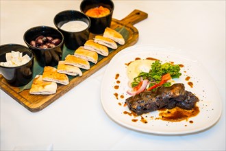 Short ribs of Beef served with bread and sauces in a white luxury table