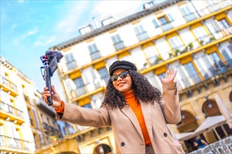Latin influencer performing a life video using a mobile phone visiting a city in winter