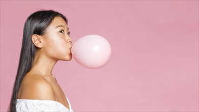 Sideways woman inflates pink balloon
