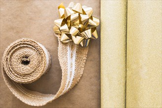Elevated view weaving ribbon golden bow with shiny gift paper