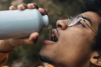 Male hiker face wearing eyeglasses drinking water from bottle