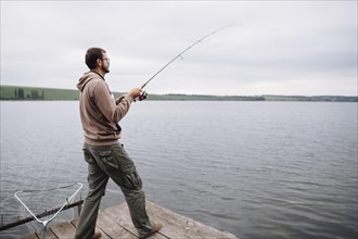 Man standing pier fishing lake