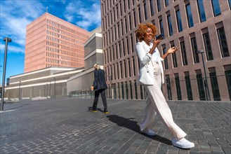 Businesswoman sending a voice message while walking next to other people outdoors