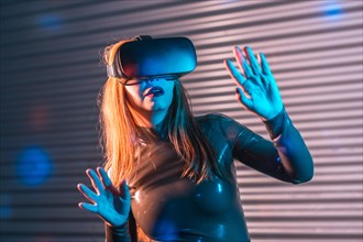 Shocked woman during an immersive game with Virtual reality goggles in an urban night space with neon lights