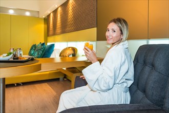 Woman dressing in bathrobe enjoying breakfast in a luxury hotel room in the morning