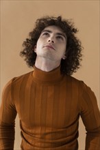 Curly haired man with brown blouse posing 5