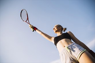 Low angle young female tennis player holding racket