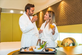 Couple in bathrobe eating a healthy breakfast in the room of an hotel