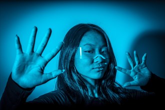 Studio photo with blue background with neon lights of chinese woman gesturing while wearing augmented reality goggles