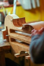 Luthier artisan violin maker carve sculpt chisel ribs of a new classical model cello in workshop Cremona Italy