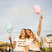Two happy female friends holding candy floss
