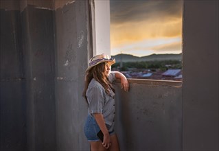 Young woman tourist looking at the sunset through an old window in Granada