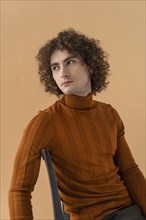 Curly haired man with brown blouse posing 9