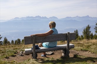 Hiker sitting on a viewing bench on the Gerlitzen