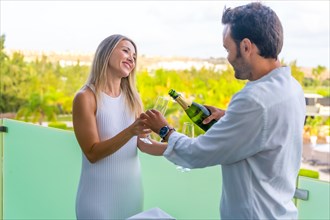 Man serving champagne to his partner in the terrace of a luxury hotel