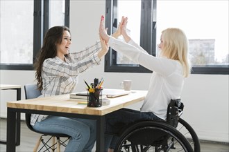 Woman wheelchair high fiving with her colleague