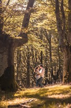 Vertical photo of a couple about to kiss embracing in the forest