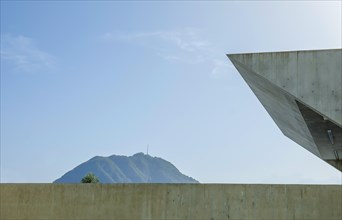 Modern Concrete Wall and Mountain Peak San Salvatore Against Blue Sky in a Sunny Day in Lugano