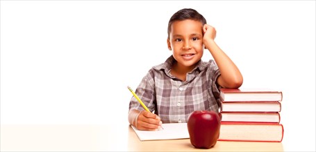 Happy young hispanic school boy at desk with books and apple isolated on a white background