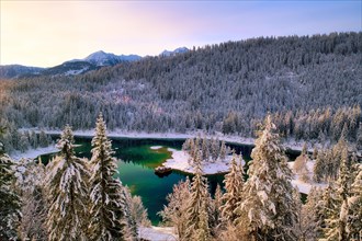 Wintery Lake Cauma in the snowy forest at sunrise